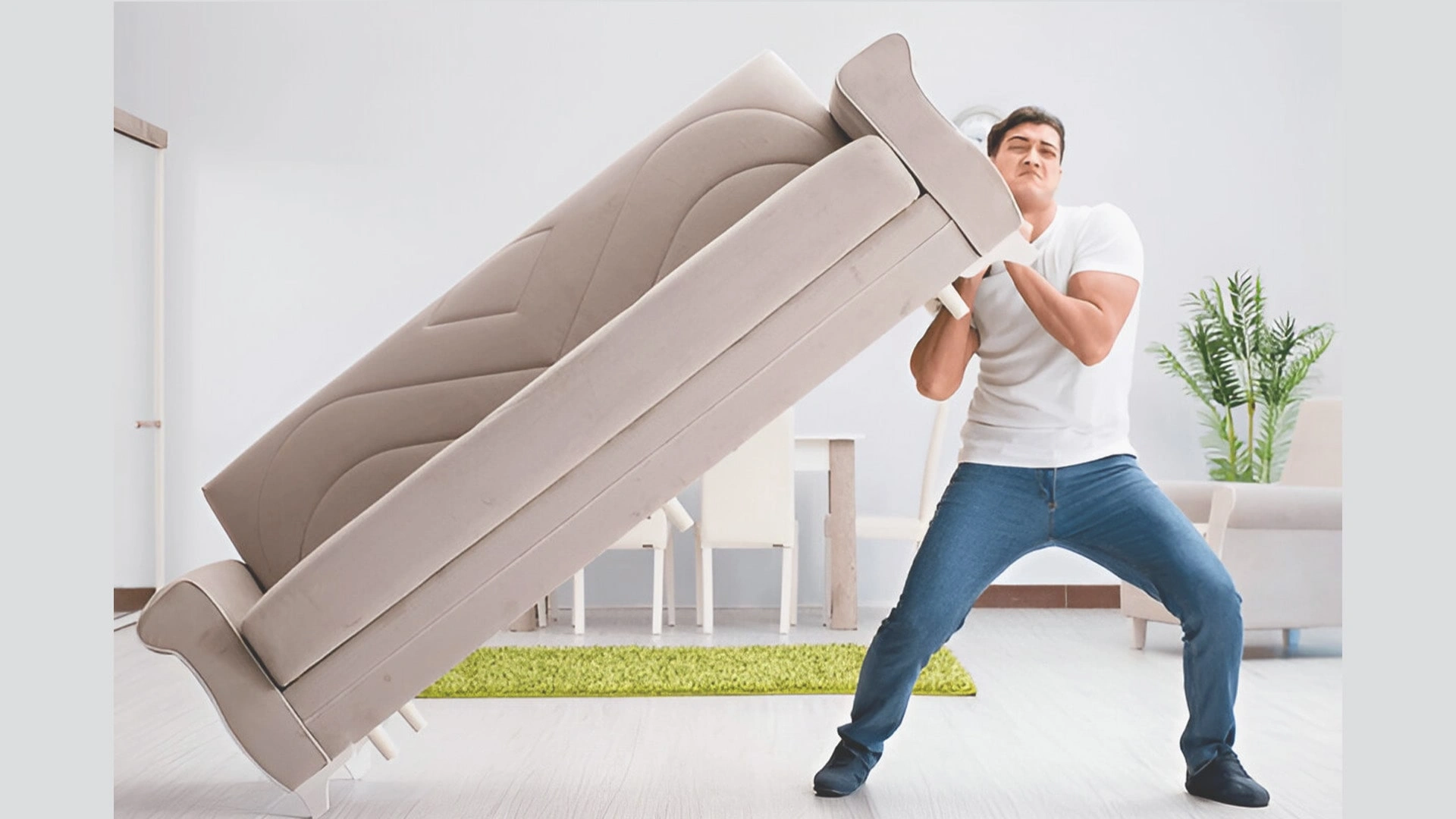 The Hassles of Owning and Moving Everything You Own Young man struggles to carry sofa